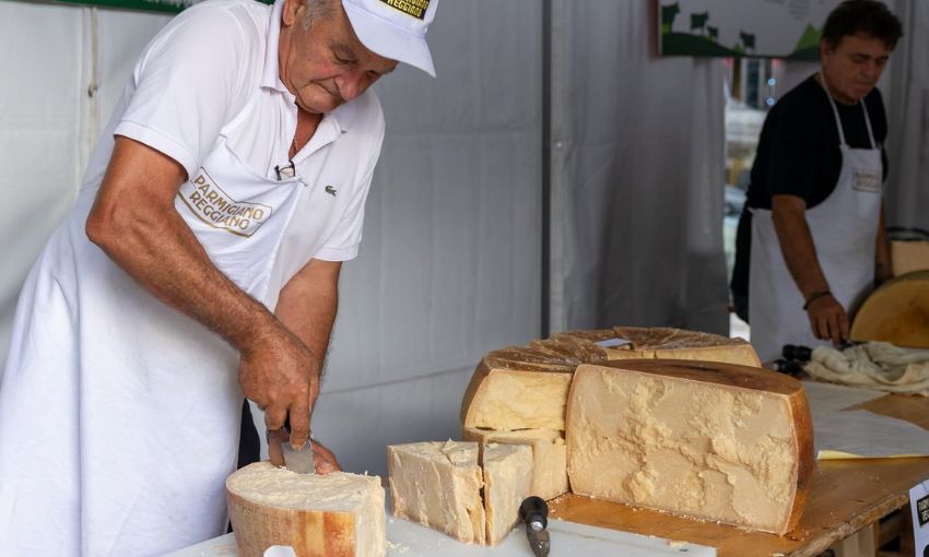 uomo che taglia pezzi di parmigiano